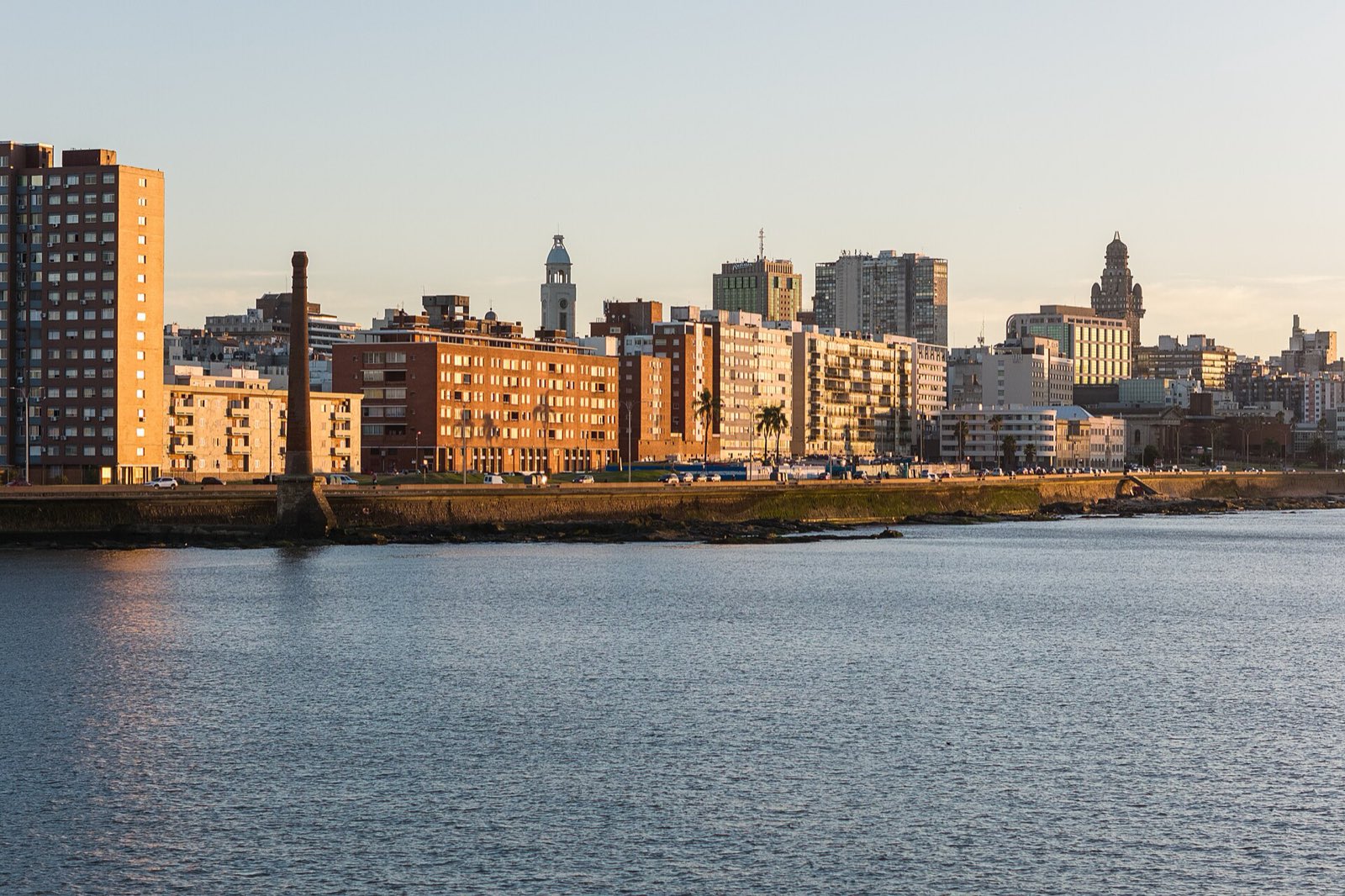 Vista aérea de la rambla de Montevideo bordeando el río, con la ciudad detrás al amanecer